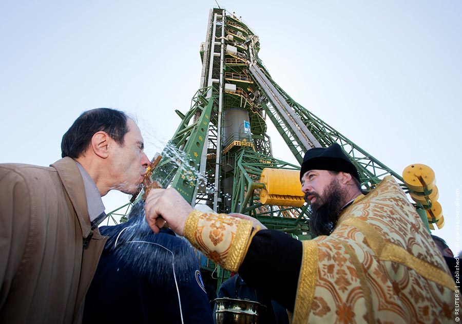 An Orthodox priest blesses a specialist in front of the Soyuz TMA-21 spacecraft at Baikonur cosmodrome