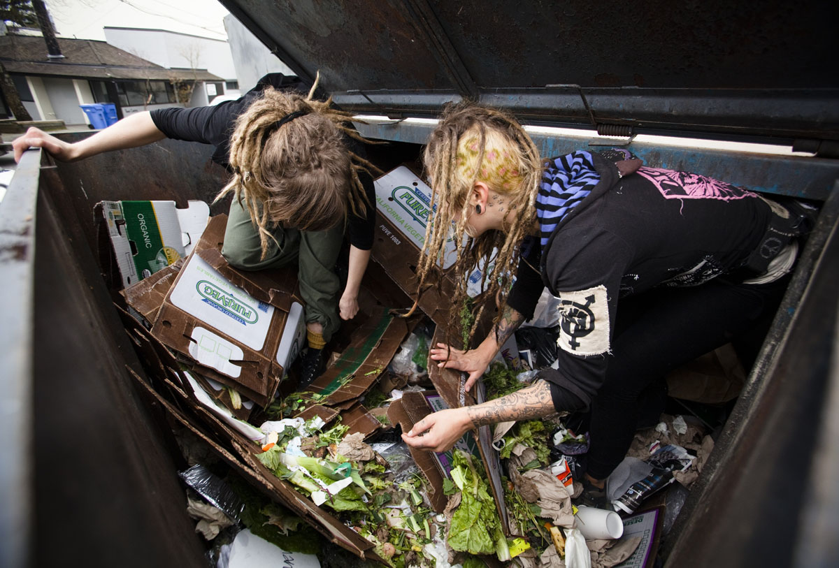 Mya Wollf, 28, and Robin Pickell sort through a dumpster for edible food in an alley behind Commercial Drive in Vancouver, British Columbia