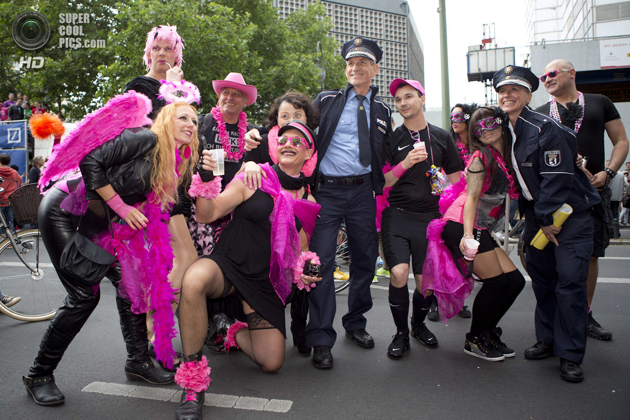 People pose with German policemen during the annual Christopher Street Day parade on Kurfuerstendamm in Berlin